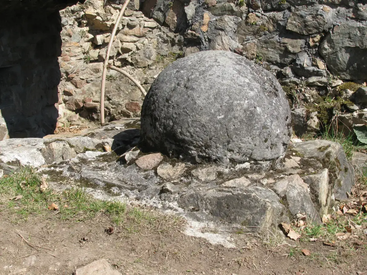 Ein großer rund zugerichteter Stein liegt zwischen den Mauern der Burgruine Tannenberg